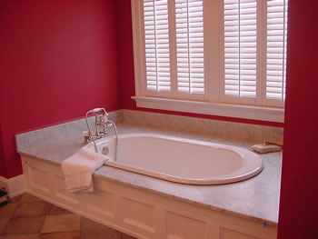 Private Residence, Chapel Hill. A vintage look drop-in tub was specified for this Chapel Hill master bath. The deck, of Carrara marble, has coordinating splashes to protect the adjacent walls. Use of such a design allows the bather to sit on the deck and easily swivel his or her legs in